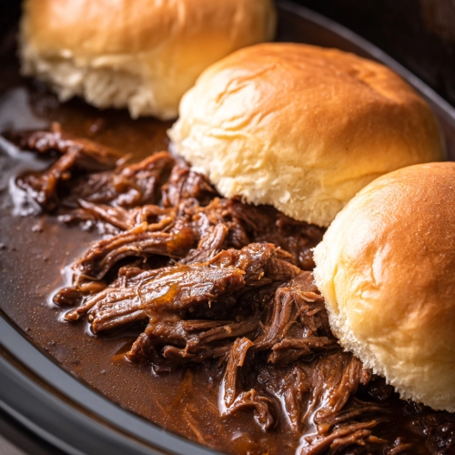 Shredded French dip beef with sandwich rolls in a slow cooker
