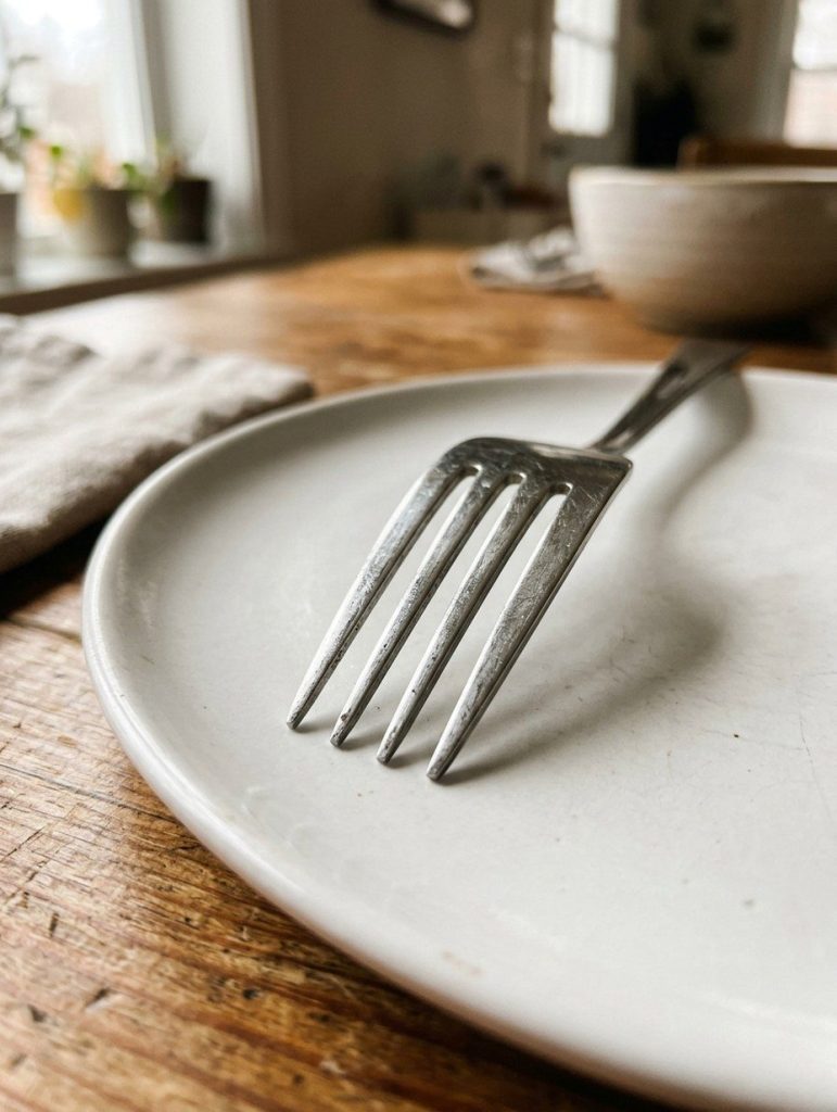 A close view of the four tines of a fork on a plate