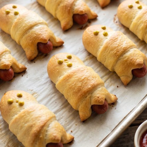 Baked hot dog ghosts on a baking sheet